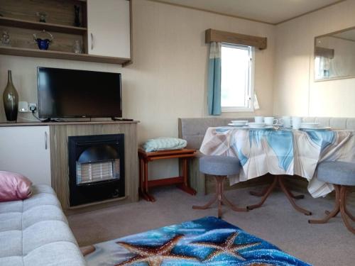 a living room with a table and a fireplace at Beautiful van, beaches, accessible pet friendly in Budleigh Salterton