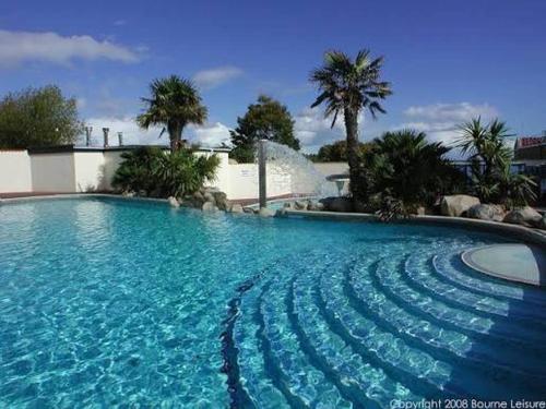 a large blue swimming pool with palm trees and a fountain at Beautiful van, beaches, accessible pet friendly in Budleigh Salterton