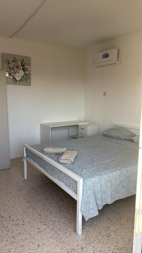 Una cama en una habitación blanca con una pared blanca. en Larnaca Ancient View Rooms, en Lárnaca