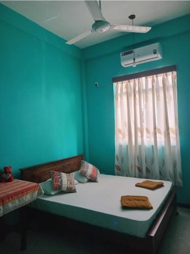 a room with a bed with blue walls and a window at Jaans Inn in Ratmalana South