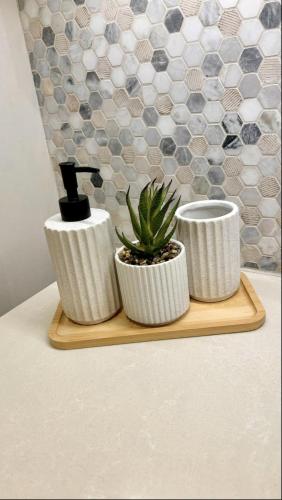 three white vases sitting on a wooden tray with a plant at Tranquil Yas Retreat Modern Mayan 3 Studio in Abu Dhabi