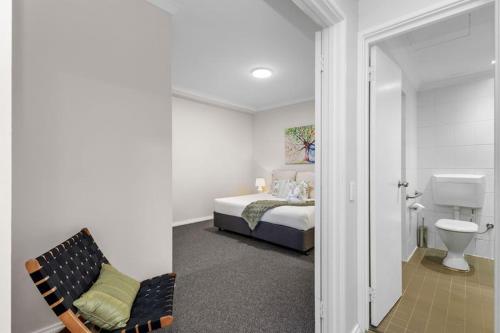 a bedroom with a bed and a bathroom with a toilet at East Perth Escape WiFi Parking in Perth