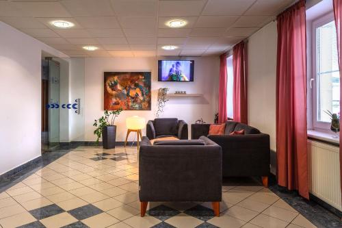a waiting room with chairs and a tv on the wall at Garni G Hotel Žilina in Žilina