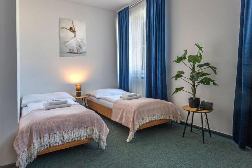 a bedroom with two beds and a potted plant at Garni G Hotel Žilina in Žilina