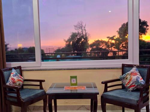a room with two chairs and a table and a window at Amoda - Best Hotel in Dharamshala in Dharamshala