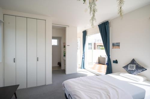 Un dormitorio con una cama blanca y una ventana grande. en KIYAZA RESORT Kamakura, en Kamakura