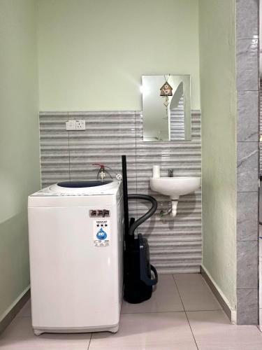 a small bathroom with a sink and a refrigerator at Specious Living Cozy House in Bukit Mertajam