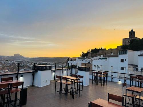 a rooftop bar with tables and chairs at sunset at Hotel Apartamentos Antequera in Antequera
