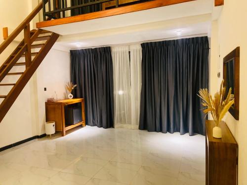 a living room with a staircase and blue curtains at Mountain Bliss - Ingiriya in Ingiriya