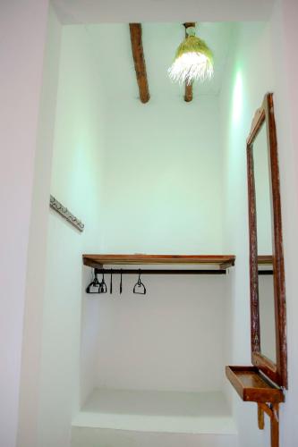 a bathroom with a mirror and a shelf on the wall at 1Zi Beachfront Resort in Paje