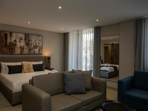 a hotel room with a bed and a couch at Lux Leisure Apartment Hotel Sandton in Johannesburg