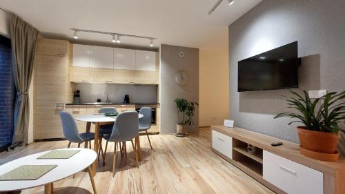 a living room with a table and chairs and a kitchen at Apartament Zakatek 2 z ogrodkiem i miejscem w garazu podziemnym in Bielsko-Biala