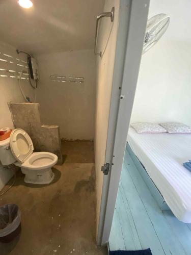 a bathroom with a toilet and a bed in a room at Patoo in Ko Chang