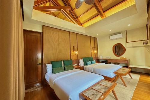 two beds in a hotel room with green pillows at Mandala Beach Resorts powered by Cocotel in Bitangan