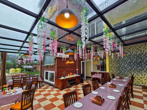 a restaurant with tables and chairs and flowers hanging from the ceiling at Amoda - Best Hotel in Dharamshala in Dharamshala
