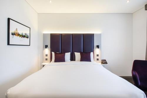 a bedroom with a large white bed and a purple chair at Premier Inn Abu Dhabi Capital Centre in Abu Dhabi