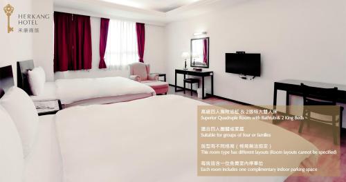 a room with a bed and a desk and a television at Herkang Hotel in Taichung