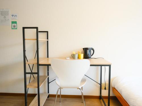 a desk with a white chair next to a bed at Osaka English House in Hirakata