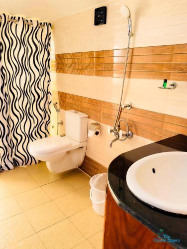 a bathroom with a toilet and a sink at The Oyster Opera in Trikarpur