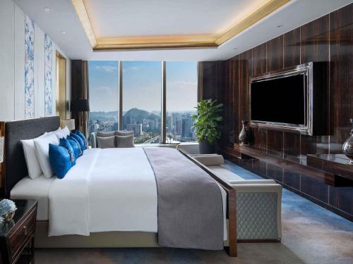 a bedroom with a large white bed and a tv at Sofitel Guiyang Hunter in Guiyang