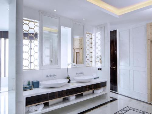 two sinks in a white bathroom with two mirrors at Sofitel Guiyang Hunter in Guiyang