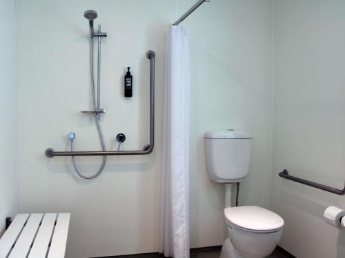 a bathroom with a toilet and a shower curtain at ibis Budget Auckland Airport in Auckland