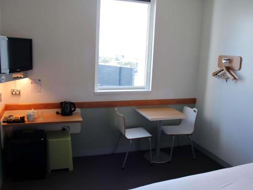 a room with a desk and a table and a window at ibis Budget Auckland Airport in Auckland
