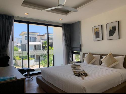 ein Schlafzimmer mit einem großen Bett und einem großen Fenster in der Unterkunft Laguna Parkside 5 bedroom villa with pool near the beach in Laguna Phuket