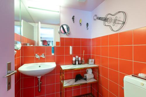 an orange tiled bathroom with a sink and a mirror at Hotel Zeit & Traum Privat SPA in Beatenberg