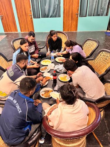 um grupo de pessoas sentadas ao redor de uma mesa comendo comida em Almost Pahadi em Chopta