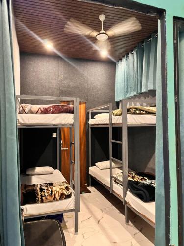 um quarto com 3 beliches e uma ventoinha de tecto em Almost Pahadi em Chopta