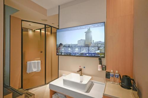 a bathroom with a sink and a tv on the wall at Huayi Select Hotel Liujiayao Subway Station Hengliutiao Branch in Beijing
