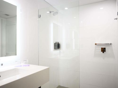 a white bathroom with a sink and a shower at Mercure Penrith in Penrith