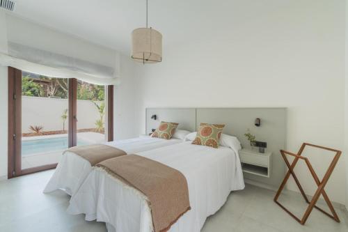 a white bedroom with a bed and a pool at Casa Aura in Novo Sancti Petri