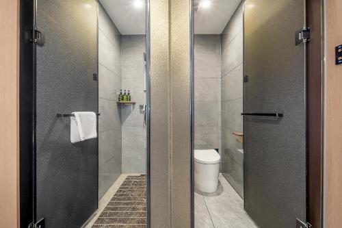 a bathroom with a toilet and a glass shower stall at Xi'an Xichen Hotel in Xi'an