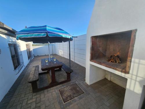 a patio with an umbrella and a table and a fireplace at Kom ma nader in Velddrif