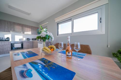 a kitchen with a wooden table with two wine glasses at Majestic Sunset Salt Lake Views 300m from beach in Larnaca