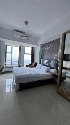 a large bedroom with a large bed and some windows at Apartemen Anderson pakuwon mall Luxury Studio Apartment Connecting Mall, Pool & City View 37B in Surabaya