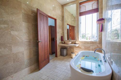 Villa Efes Bali في سمينياك: حمام كبير مع حوض ومغسلة