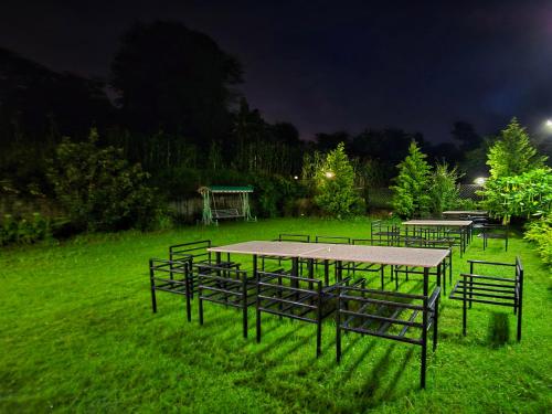 a group of tables and benches in a field at night at Amoda - Best Hotel in Dharamshala in Dharamshala