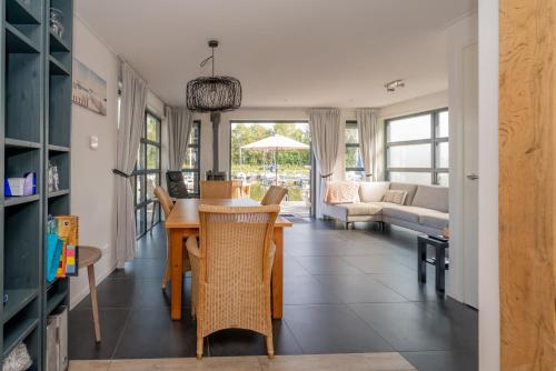 a dining room and living room with a table and chairs at Nautic Rentals - Watervilla's Zuiderhoeve in De Heen