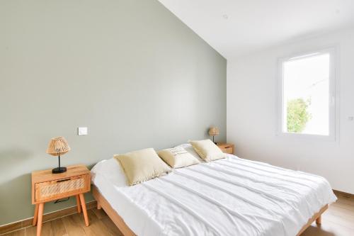 ein weißes Schlafzimmer mit einem Bett und einem Fenster in der Unterkunft Plage à 400 m - Maison pour 4 avec terrasse in La Guérinière