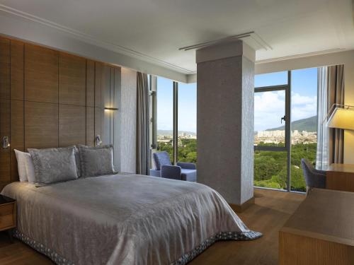 ブルサにあるMövenpick Hotel & Thermal Spa Bursaの大きなベッドと大きな窓のある寝室