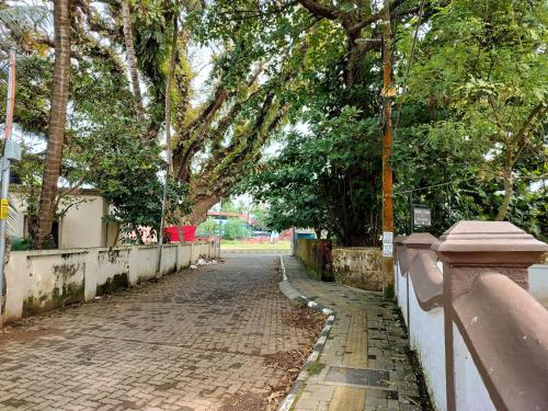 a cobblestone street with trees and a fence at Honza Hostel in Cochin