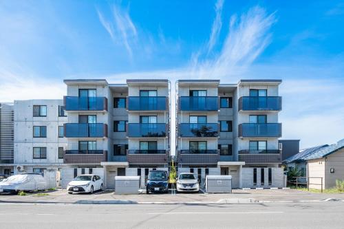 an apartment building with cars parked in a parking lot at SERAPHIC 千歳MS101 in Chitose