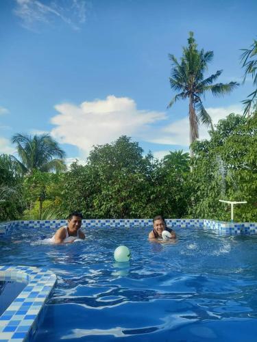 two people swimming in a swimming pool at Mischa Hostel in Dauis