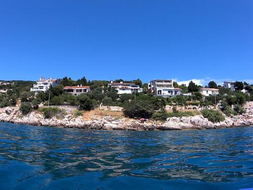 un groupe de maisons sur une île dans l'eau dans l'établissement Apartments Peric, à Baška