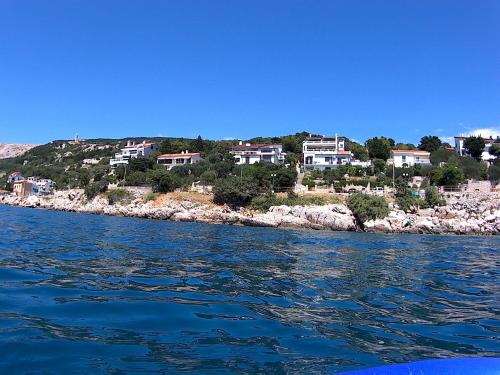 un groupe de maisons sur une colline à côté de l'eau dans l'établissement Apartments Peric, à Baška