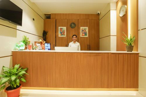 a woman is standing behind a counter in a lobby at Fabhotel Nexus Inn near Nesco in Mumbai