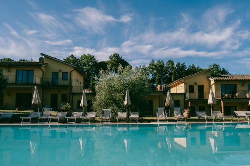 a large swimming pool with chairs and umbrellas at Fattoria degli Usignoli in San Donato in Fronzano